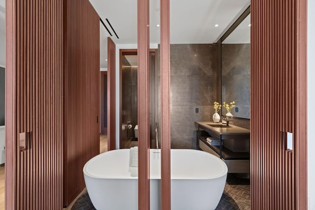 full bath with a soaking tub, brick floor, tile walls, and vanity