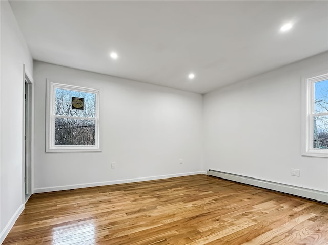 unfurnished room with baseboard heating and light wood-type flooring