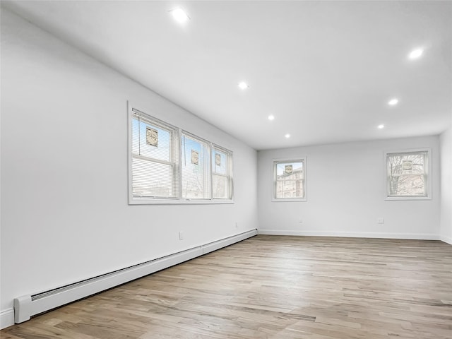 unfurnished room with baseboard heating and light hardwood / wood-style flooring