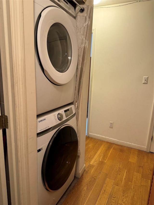 clothes washing area with light hardwood / wood-style floors and stacked washing maching and dryer