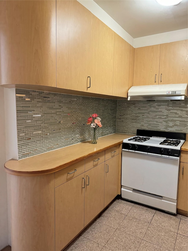 kitchen featuring stove, backsplash, and light brown cabinetry