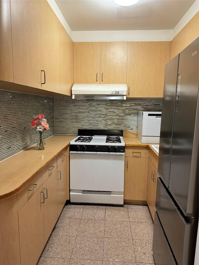 kitchen with light brown cabinetry, white stove, stainless steel refrigerator, and tasteful backsplash