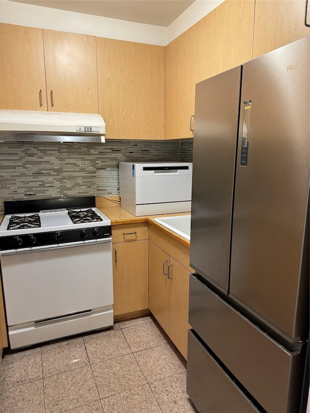 kitchen featuring backsplash, white stove, sink, light brown cabinetry, and stainless steel refrigerator