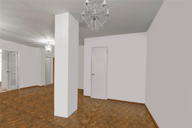 spare room with dark parquet flooring and an inviting chandelier