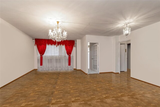 empty room with an inviting chandelier and parquet floors