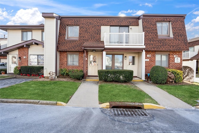 multi unit property with a balcony and a front lawn