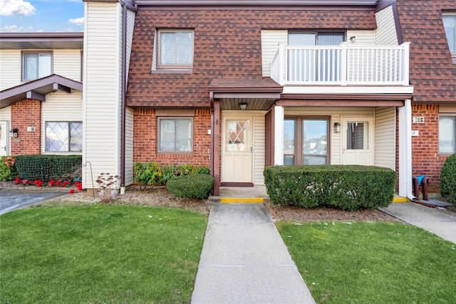 townhome / multi-family property with a balcony and a front lawn