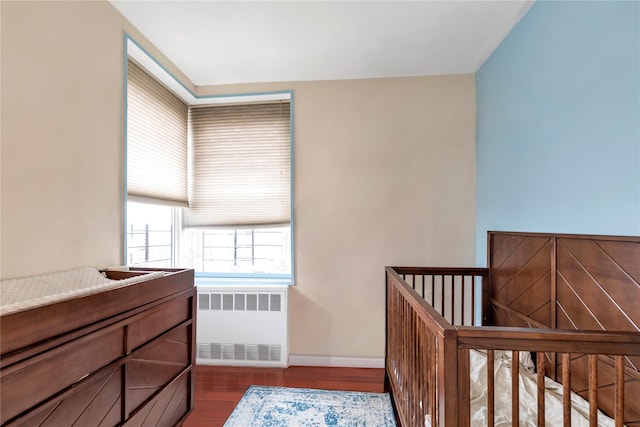 bedroom with dark hardwood / wood-style floors and radiator