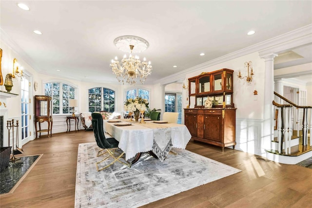 dining room featuring a high end fireplace, crown molding, dark hardwood / wood-style floors, ornate columns, and a chandelier