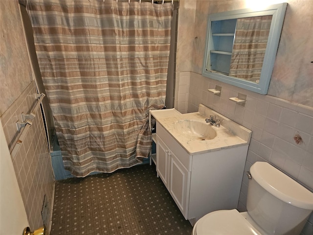 bathroom with vanity, toilet, and tile walls