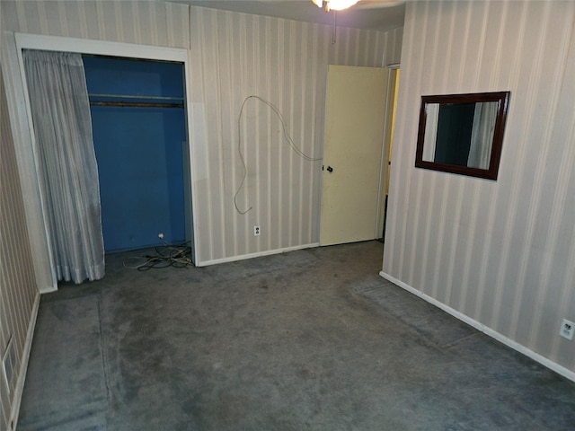 unfurnished bedroom featuring dark carpet and a closet