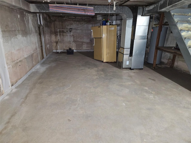 basement with white refrigerator, gas water heater, and heating unit