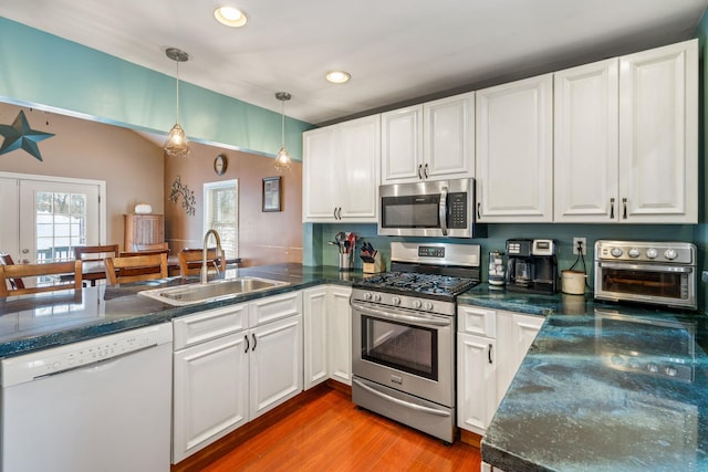 kitchen with decorative light fixtures, sink, white cabinetry, and stainless steel appliances