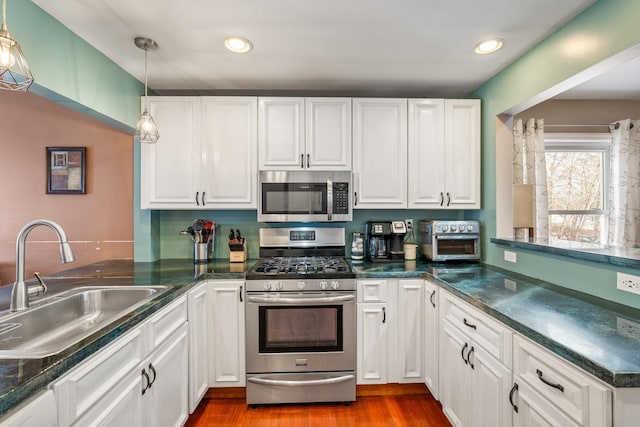 kitchen with white cabinetry, sink, dark wood-type flooring, hanging light fixtures, and stainless steel appliances