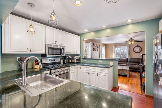 kitchen featuring white cabinets, sink, appliances with stainless steel finishes, decorative light fixtures, and kitchen peninsula