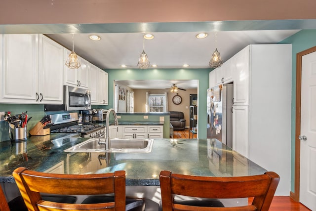 kitchen with ceiling fan, hanging light fixtures, stainless steel appliances, kitchen peninsula, and white cabinets