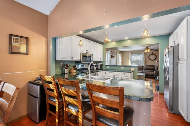 kitchen featuring a kitchen breakfast bar, white cabinetry, kitchen peninsula, and stainless steel appliances