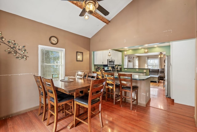 dining space with ceiling fan, light hardwood / wood-style floors, and high vaulted ceiling