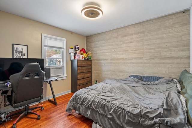 bedroom featuring wood walls, wood-type flooring, and cooling unit