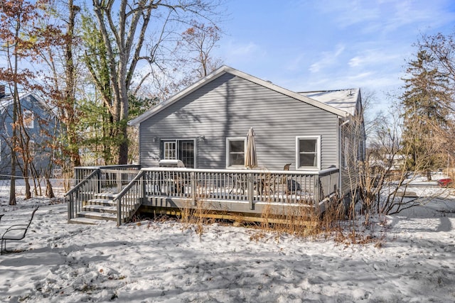 snow covered back of property with a wooden deck