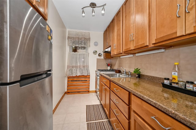 kitchen featuring stainless steel appliances, tasteful backsplash, dark stone counters, and sink