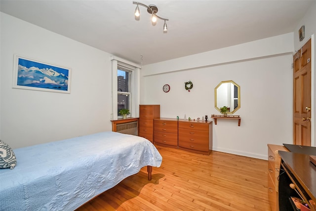 bedroom featuring radiator heating unit and light hardwood / wood-style flooring