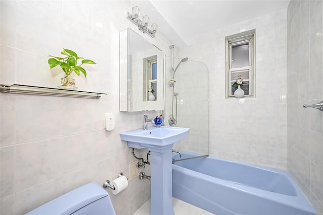 full bathroom with sink, tiled shower / bath, tile walls, and toilet