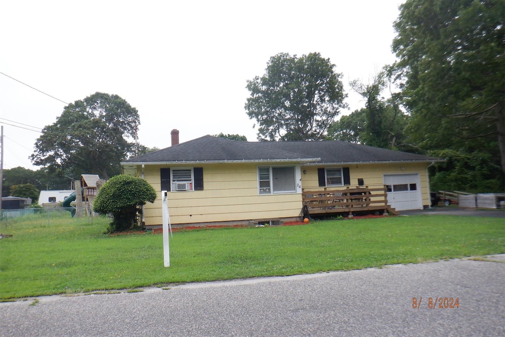 ranch-style home featuring a front yard, a deck, cooling unit, and a garage