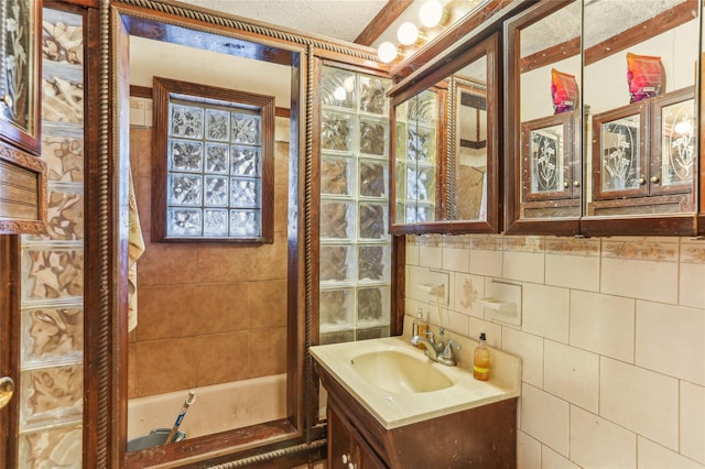 bathroom featuring a textured ceiling, vanity, and tile walls