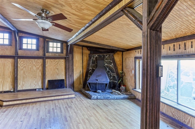 interior space with light wood-type flooring, wood ceiling, ceiling fan, lofted ceiling with beams, and wood walls