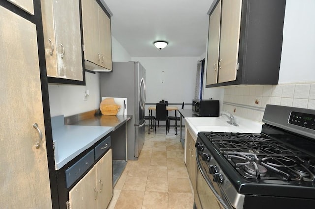 kitchen with decorative backsplash, light tile patterned floors, light brown cabinetry, and appliances with stainless steel finishes