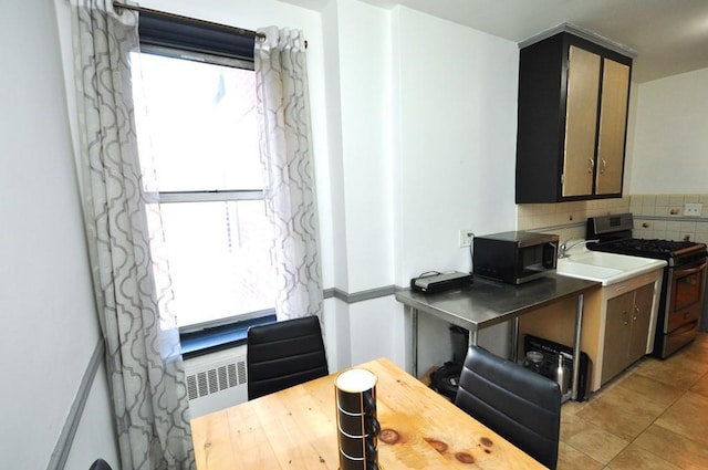 kitchen with gas range, decorative backsplash, and radiator heating unit