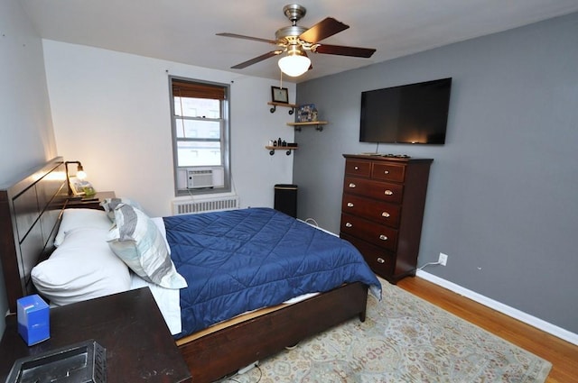 bedroom featuring radiator heating unit, ceiling fan, cooling unit, and hardwood / wood-style floors