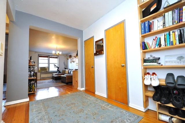 hall featuring hardwood / wood-style floors, a notable chandelier, and radiator