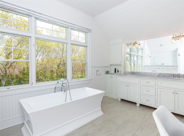 bathroom featuring a bathing tub, a healthy amount of sunlight, vanity, and lofted ceiling