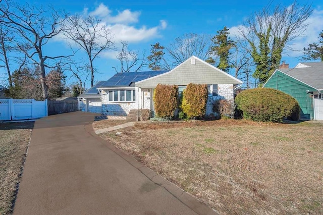 ranch-style house with a front yard and solar panels