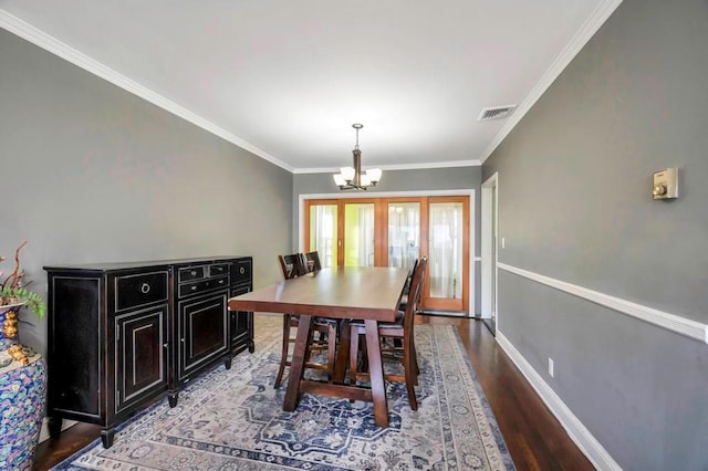 dining area featuring hardwood / wood-style flooring, an inviting chandelier, ornamental molding, and french doors