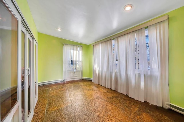 empty room featuring lofted ceiling and a baseboard heating unit