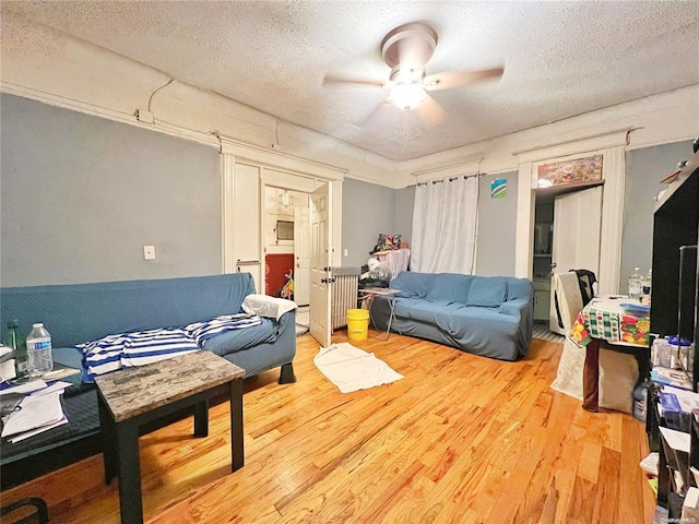 living room featuring ceiling fan, wood-type flooring, and a textured ceiling