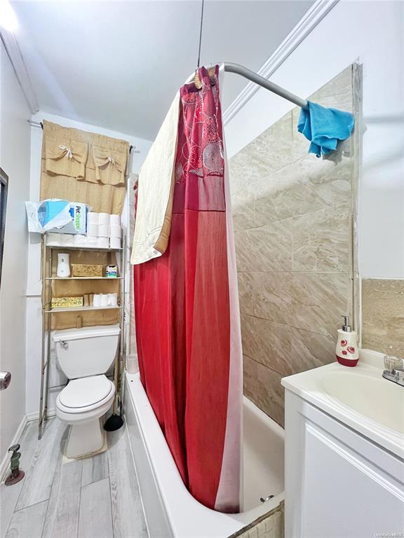 full bathroom with shower / bath combo, vanity, hardwood / wood-style flooring, and toilet