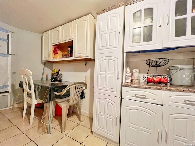 kitchen featuring white cabinets, light tile patterned flooring, and light stone countertops