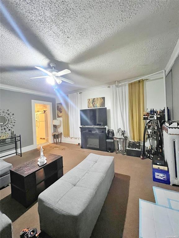 living room featuring crown molding, ceiling fan, and a textured ceiling