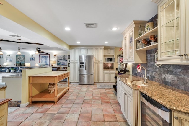 kitchen featuring cream cabinets, hanging light fixtures, beverage cooler, and stainless steel appliances