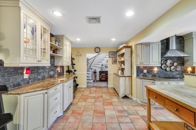 kitchen featuring decorative backsplash, black cooktop, wall chimney exhaust hood, and sink