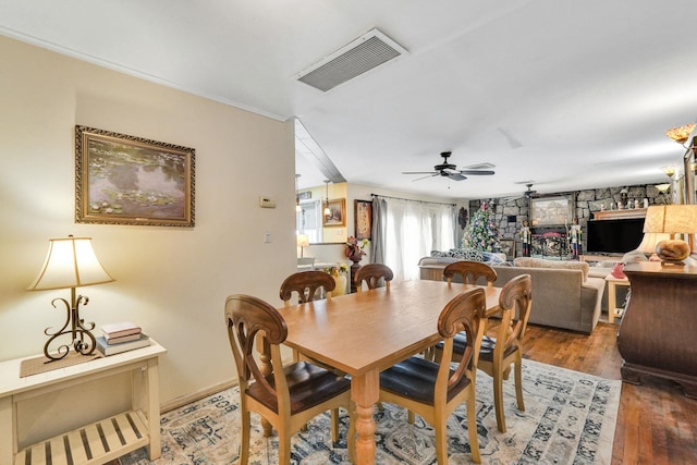 dining space with dark hardwood / wood-style floors, ceiling fan, and a fireplace