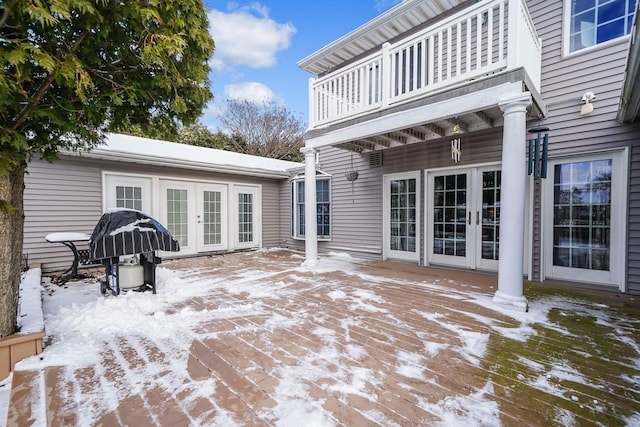 snow covered patio with french doors and a balcony