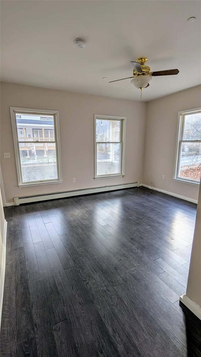 spare room featuring dark hardwood / wood-style floors, ceiling fan, and a baseboard heating unit