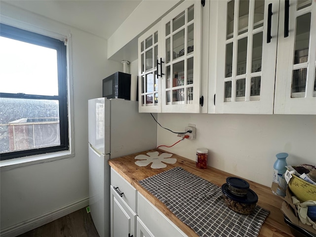 kitchen featuring white cabinetry, white fridge, and dark wood-type flooring