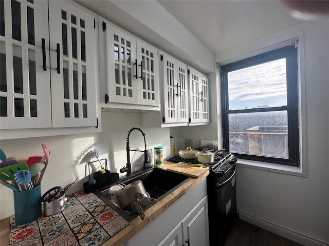 kitchen featuring gas stove, sink, white cabinets, and dark hardwood / wood-style floors