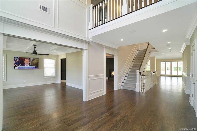 unfurnished living room featuring visible vents, ornamental molding, dark wood-style floors, ceiling fan, and stairs